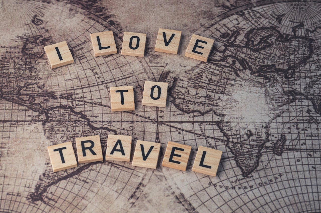 Wood scrabble tiles spelling 'I Love to Travel' on a vintage map.