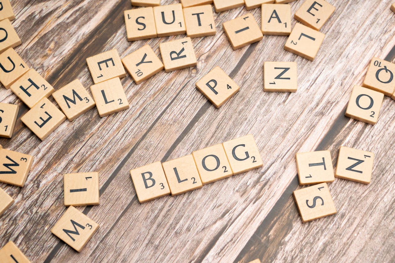 Scattered wooden letter tiles spelling 'Blog' on a rustic wood background.